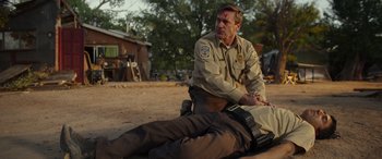 Movie still from “Maggie Moore(s)” (2023), directed by John Slattery – A man in a uniform is sitting on the ground; Medium shot, Over the shoulder angle