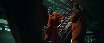 Movie still from “Maggie Moore(s)” (2023), directed by John Slattery – A man that is wearing orange and is going down the stairs; Medium shot, Low angle