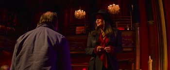 Movie still from “Magic Mike's Last Dance” (2023), directed by Steven Soderbergh – A woman wearing a black hat and a red scarf; Medium shot, Over the shoulder angle