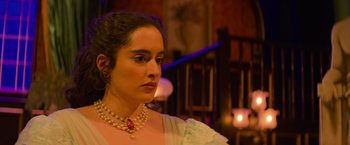 Movie still from “Magic Mike's Last Dance” (2023), directed by Steven Soderbergh – A woman wearing a pearl necklace looking to her left; Close Up shot, Over the shoulder angle