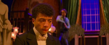 Movie still from “Magic Mike's Last Dance” (2023), directed by Steven Soderbergh – A man in a suit and bow tie looking at the camera; Close Up shot, Over the shoulder angle