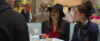 Movie still from “Magic Mike's Last Dance” (2023), directed by Steven Soderbergh – A woman sitting at a table with a glass of wine; Medium shot, Over the shoulder angle