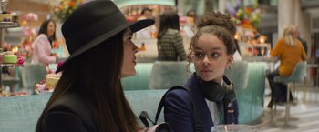 Movie still from “Magic Mike's Last Dance” (2023), directed by Steven Soderbergh – A woman wearing a hat talking to a woman wearing glasses; Close Up shot, Over the shoulder angle