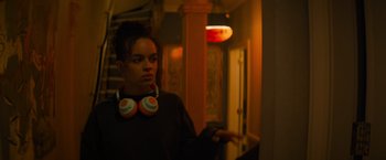 Movie still from “Magic Mike's Last Dance” (2023), directed by Steven Soderbergh – A woman with headphones standing in a room; Medium shot, Over the shoulder angle