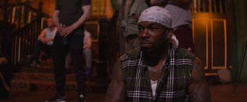 Movie still from “Magic Mike's Last Dance” (2023), directed by Steven Soderbergh – A man with a bandanna is sitting in a room; Medium shot, Over the shoulder angle