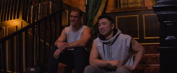 Movie still from “Magic Mike's Last Dance” (2023), directed by Steven Soderbergh – Two young men sitting next to each other in a room; Medium shot, Low angle
