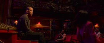 Movie still from “Magic Mike's Last Dance” (2023), directed by Steven Soderbergh – A man sitting on a chair in front of another man; Wide shot, Over the shoulder angle