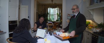 Movie still from “Magic Mike's Last Dance” (2023), directed by Steven Soderbergh – A group of people sitting at a table with food; Medium shot, Over the shoulder angle