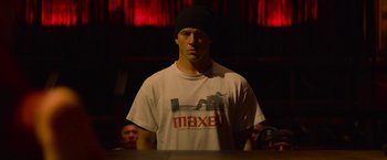 Movie still from “Magic Mike's Last Dance” (2023), directed by Steven Soderbergh – A man in a white t - shirt wearing a black hat; Medium shot, Low angle