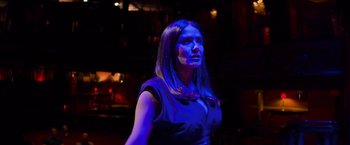 Movie still from “Magic Mike's Last Dance” (2023), directed by Steven Soderbergh – A woman with long hair standing in a dark room; Medium shot, Low angle