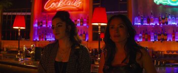 Movie still from “Magic Mike's Last Dance” (2023), directed by Steven Soderbergh – Two women are standing in front of a neon sign; Medium shot, Over the shoulder angle