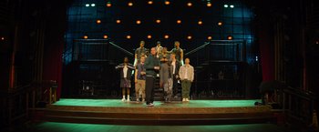 Movie still from “Magic Mike's Last Dance” (2023), directed by Steven Soderbergh – A group of people standing on top of a stage; Wide shot, High angle