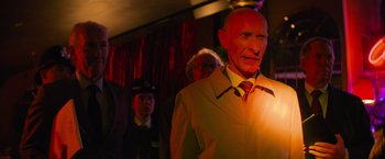 Movie still from “Magic Mike's Last Dance” (2023), directed by Steven Soderbergh – A man in a suit and tie standing in front of other people; Medium shot, Low angle