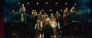 Movie still from “Magic Mike's Last Dance” (2023), directed by Steven Soderbergh – A group of men standing on top of a set of stairs; Wide shot, Low angle