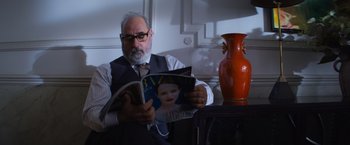 Movie still from “Magic Mike's Last Dance” (2023), directed by Steven Soderbergh – An older man sitting at a table reading a magazine; Close Up shot, Low angle