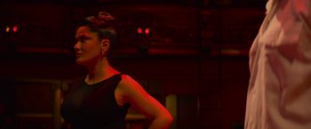Movie still from “Magic Mike's Last Dance” (2023), directed by Steven Soderbergh – A woman in a black dress standing in front of a red light; Medium shot, Low angle