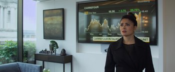 Movie still from “Magic Mike's Last Dance” (2023), directed by Steven Soderbergh – A woman standing in front of a large screen television; Medium shot, Over the shoulder angle