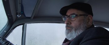 Movie still from “Magic Mike's Last Dance” (2023), directed by Steven Soderbergh – A man with a beard wearing glasses in a car; Close Up shot, Low angle