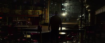 Movie still from “Magic Mike's Last Dance” (2023), directed by Steven Soderbergh – A man standing on a stage in the dark; Extreme Wide shot, Low angle