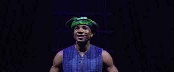 Movie still from “Magic Mike's Last Dance” (2023), directed by Steven Soderbergh – A man wearing a green hat and a blue shirt; Close Up shot, Low angle