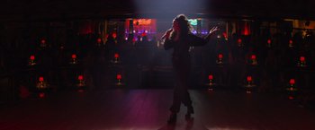Movie still from “Magic Mike's Last Dance” (2023), directed by Steven Soderbergh – A woman is dancing in a bar at night; Wide shot, Low angle