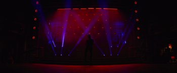 Movie still from “Magic Mike's Last Dance” (2023), directed by Steven Soderbergh – A man standing in front of a stage with lights; Extreme Wide shot, Low angle