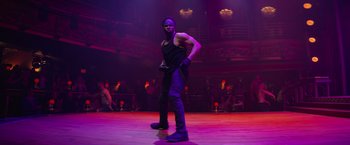 Movie still from “Magic Mike's Last Dance” (2023), directed by Steven Soderbergh – A man in black shirt and black pants on a stage; Wide shot, Low angle