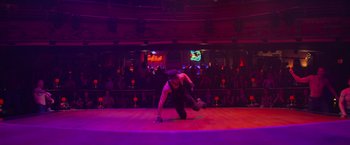 Movie still from “Magic Mike's Last Dance” (2023), directed by Steven Soderbergh – A man is performing a dance on a stage in front of an audience; Wide shot, High angle