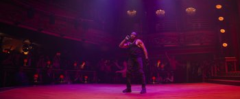 Movie still from “Magic Mike's Last Dance” (2023), directed by Steven Soderbergh – A man in a black shirt is on a stage; Wide shot, Low angle