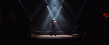 Movie still from “Magic Mike's Last Dance” (2023), directed by Steven Soderbergh – A man standing on a stage in the middle of a show; Wide shot, Low angle