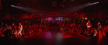 Movie still from “Magic Mike's Last Dance” (2023), directed by Steven Soderbergh – A crowd of people sitting on a stage in front of a red light; Extreme Wide shot, High angle