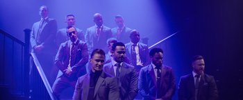 Movie still from “Magic Mike's Last Dance” (2023), directed by Steven Soderbergh – A group of men standing in front of each other in suits; Wide shot, Over the shoulder angle