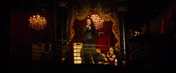 Movie still from “Magic Mike's Last Dance” (2023), directed by Steven Soderbergh – A woman standing on a stage holding a microphone; Wide shot, Low angle