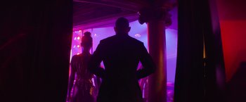 Movie still from “Magic Mike's Last Dance” (2023), directed by Steven Soderbergh – A man and a woman standing in front of a purple light; Wide shot, Low angle
