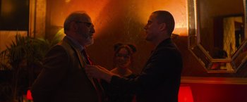 Movie still from “Magic Mike's Last Dance” (2023), directed by Steven Soderbergh – A man and a woman standing next to each other while a man adjusts a tie; Medium shot, Over the shoulder angle