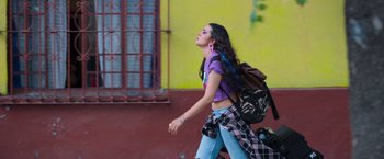 Movie still from “Making It Up” (2023), directed by Guillermo Calderón – A young girl walking down the street with a backpack; Medium shot, Low angle