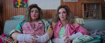 Movie still from “Making It Up” (2023), directed by Guillermo Calderón – A couple of women sitting next to each other on top of a couch; Medium shot, High angle