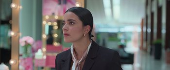 Movie still from “Making It Up” (2023), directed by Guillermo Calderón – A woman in a black jacket and a white neck tie; Close Up shot, Over the shoulder angle