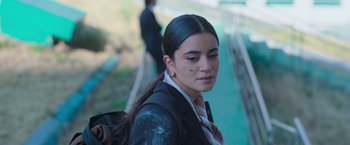 Movie still from “Making It Up” (2023), directed by Guillermo Calderón – A woman with a black jacket and a red tie; Close Up shot, High angle