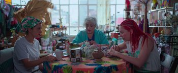Movie still from “Making It Up” (2023), directed by Guillermo Calderón – A woman sitting at a table with two other women; Medium shot, High angle