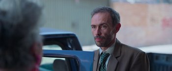 Movie still from “Making It Up” (2023), directed by Guillermo Calderón – A person wearing a suit and tie; Close Up shot, Low angle