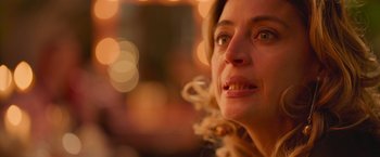 Movie still from “Making It Up” (2023), directed by Guillermo Calderón – A woman's face with lights in the background; Close Up shot, Over the shoulder angle