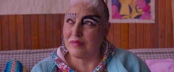 Movie still from “Making It Up” (2023), directed by Guillermo Calderón – A woman with white blonde hair and black eye make up; Close Up shot, Over the shoulder angle