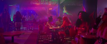 Movie still from “Making It Up” (2023), directed by Guillermo Calderón – A group of people sitting at a table in a room; Wide shot, High angle