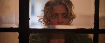 Movie still from “Making It Up” (2023), directed by Guillermo Calderón – A woman looking out a window at the camera; Close Up shot, Low angle