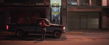 Movie still from “Making It Up” (2023), directed by Guillermo Calderón – A woman standing in front of a pick - up truck; Extreme Wide shot, Over the shoulder angle