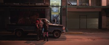 Movie still from “Making It Up” (2023), directed by Guillermo Calderón – A group of people standing next to a truck on the side of the road; Extreme Wide shot, High angle
