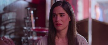 Movie still from “Making It Up” (2023), directed by Guillermo Calderón – A person sitting in a room; Close Up shot, Over the shoulder angle