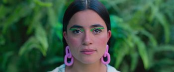 Movie still from “Making It Up” (2023), directed by Guillermo Calderón – A young woman with pink and green eye makeup; Close Up shot, Overhead angle