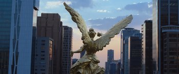 Movie still from “Making It Up” (2023), directed by Guillermo Calderón – A statue of an archangel in the middle of a city; Extreme Wide shot, High angle